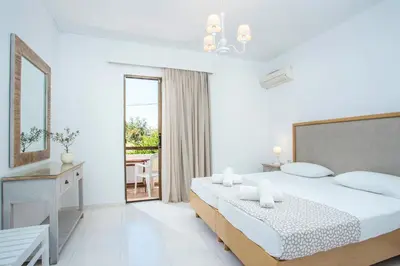 a white bedroom with a bed and a balcony at Voula Studios in Faliraki