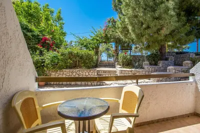 a patio with a table and chairs and trees at Voula Studios in Faliraki