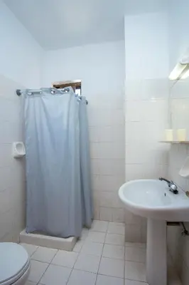 a white bathroom with a shower curtain and a sink at Voula Studios in Faliraki