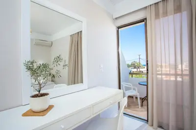 a white bathroom with a mirror and a plant at Voula Studios in Faliraki