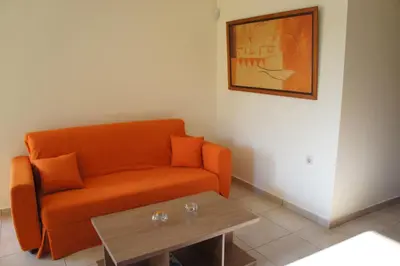an orange couch in a living room with a table at Ixia Beach in Ialyssos