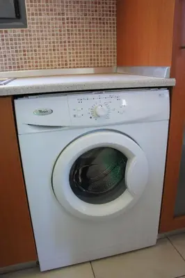 a white washing machine under a counter in a kitchen at Ixia Beach in Ialyssos