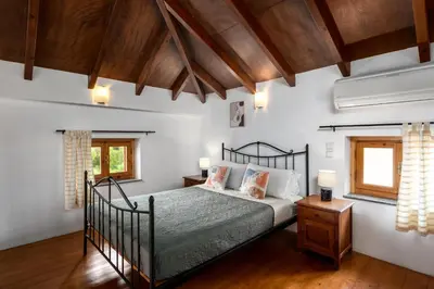 a bedroom with a bed and two windows at Over The Sea Apartments in Symi