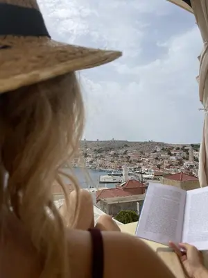 a woman in a straw hat reading a book at Marina Castellana Studios in Halki