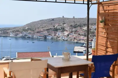 a table and chairs on a balcony with a view of a harbor at Marina Castellana Studios in Halki