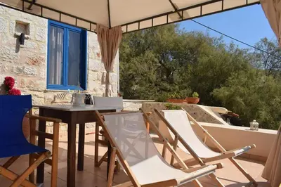 a patio with chairs and a table and a window at Marina Castellana Studios in Halki
