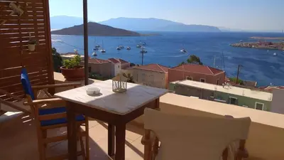 a table and chairs on a balcony with a view of the water at Marina Castellana Studios in Halki