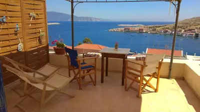 a table and chairs on a balcony with a view of the ocean at Marina Castellana Studios in Halki