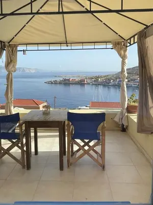a table and chairs on a balcony with a view of the water at Marina Castellana Studios in Halki