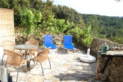 a patio with blue chairs and a table and a stone wall at O Ioannis in Kritinía