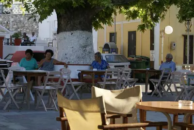 a group of women sitting at tables under a tree at O Ioannis in Kritinía