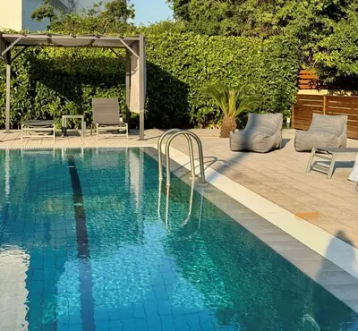 a swimming pool with two chairs and an umbrella at Villa Katrin in Ialyssos