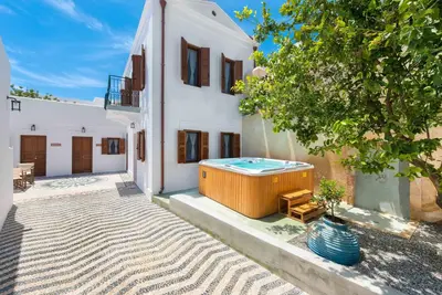 a large white house with a hot tub in the yard at Villa Eftihia in Lindos in Líndos
