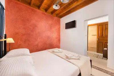 a bedroom with a white bed and a red wall at Villa Eftihia in Lindos in Líndos