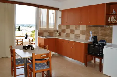 a kitchen with wooden cabinets and a table with a microwave at Sky-Line Apartments in Afantou