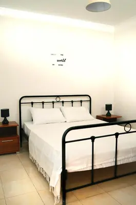 a bedroom with a bed with white sheets and two tables at Sky-Line Apartments in Afantou