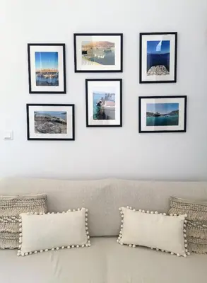 a row of framed pictures on a wall above a couch at Villa Miranda in Halki