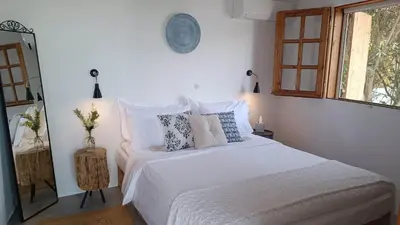 a bedroom with a white bed with pillows and a window at Ktima Natura in Archangelos