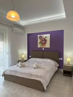 a bedroom with a large bed with a purple wall at Iliana Apartment in Afantou