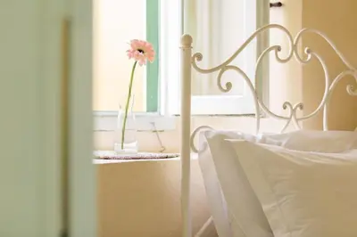 a white bed with a vase with a flower in a window at Aerino in Symi