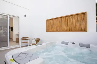 a bath tub in a room with a table at Stay Helios in Faliraki