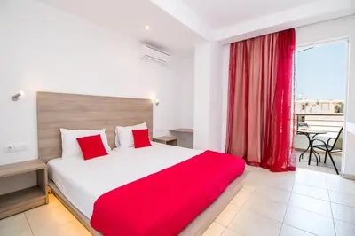 a bedroom with a large bed with a red blanket at Stay Helios in Faliraki