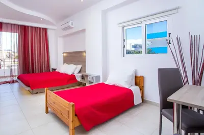 a hotel room with two beds and a window at Stay Helios in Faliraki