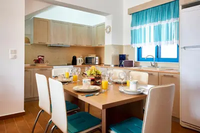 a kitchen with a wooden table with chairs and a dining room at Nerida Beachfront Villas in Plimmiri