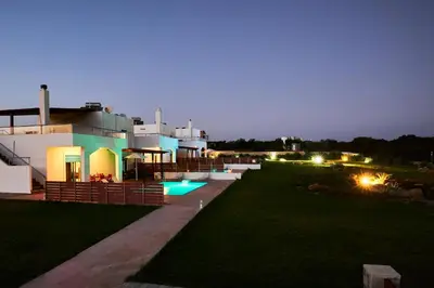 a large house with a swimming pool at night at Nerida Beachfront Villas in Plimmiri