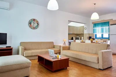 a living room with two couches and a table with a laptop at Nerida Beachfront Villas in Plimmiri