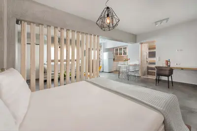 a bedroom with a large white bed and a kitchen at Lindos 4 me Apartment in Líndos