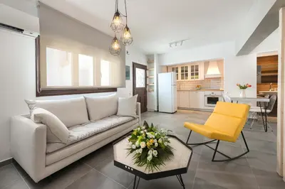 a living room with a white couch and a yellow chair at Lindos 4 me Apartment in Líndos