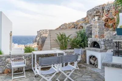 a patio with a table and chairs and a stone fireplace at Lindos 4 me Apartment in Líndos