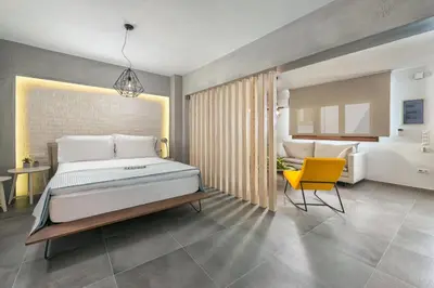 a bedroom with a large bed and a yellow chair at Lindos 4 me Apartment in Líndos
