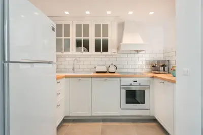 a white kitchen with white cabinets and appliances at Lindos 4 me Apartment in Líndos