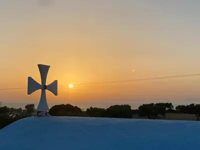 a cross on top of a roof with the sunset in the background at Summer View in Theologos