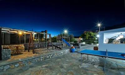 a playground at night with a slide and swings at Maripaul Family Villa in Lardos