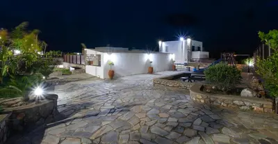 a patio at night with a white building and lights at Maripaul Family Villa in Lardos