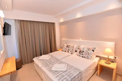 a bedroom with a large white bed and a television at Island Dreams Rooms & Suites in Rhodes Town
