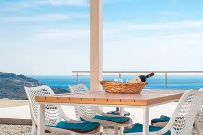 a table with chairs and a basket of wine on a balcony at Villa Olympos in Afantou