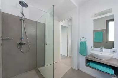 a bathroom with a glass shower and a sink at Villa Olympos in Afantou