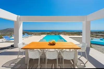 a table and chairs on a patio with a pool at Villa Olympos in Afantou