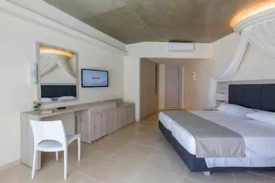 a bedroom with a bed and a desk and a television at Rodos Star Hotel in Afantou