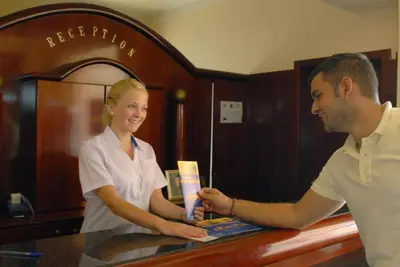 a man and a woman standing at a counter at Rodos Star Hotel in Afantou