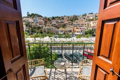 a balcony with chairs and a view of a city at Myrtia in Symi