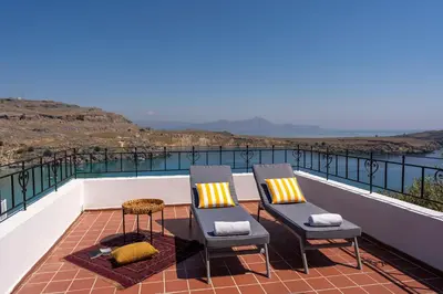 two chairs and a table on a balcony with a view at Maris Lindos Suites & Apartments in Líndos
