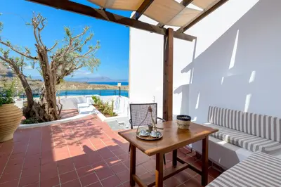 a patio with a table and a view of the ocean at Maris Lindos Suites & Apartments in Líndos