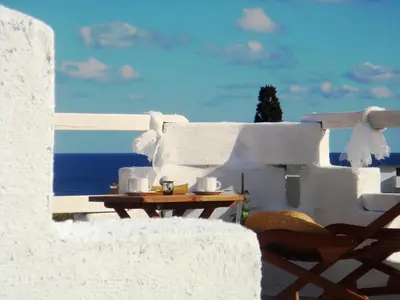 a table with cups on top of a white building at Blugreen Stegna Suites and Apartments in Archangelos
