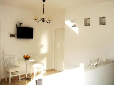 a white living room with a table and a tv at Blugreen Stegna Suites and Apartments in Archangelos