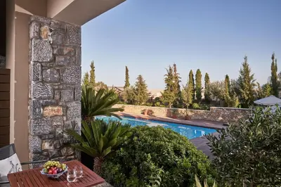 a patio with a table and a swimming pool at Aquagrand Artistic Luxury Beach Resort - Adults Only in Líndos